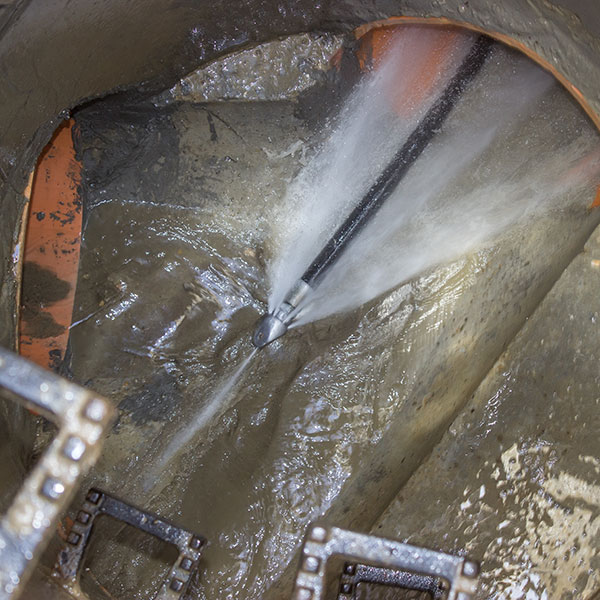 plumber cleaning pipe using hydro jetting equipment